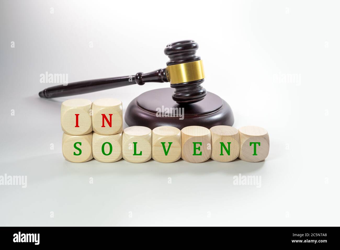 Holzwürze mit dem Wort insolvent und einem Richtergavel, einige Firmen müssen während der Coronavirus-Krise aufgeben, grauer Hintergrund mit Kopierraum, Stockfoto
