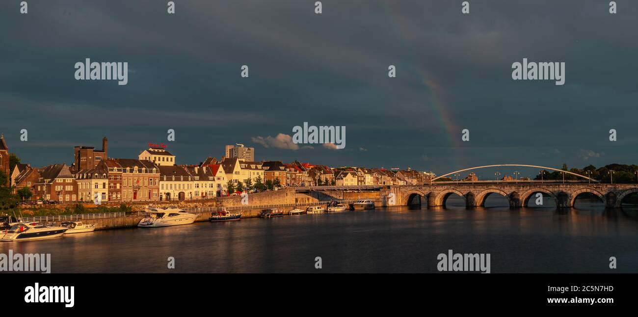 Skyline von Maastricht mit dem kommenden Gebiet Wyck und der Sint Servaas Brücke nach einem Sommerabend Sturm in der goldenen Stunde mit einem Regenbogen zeigen Stockfoto