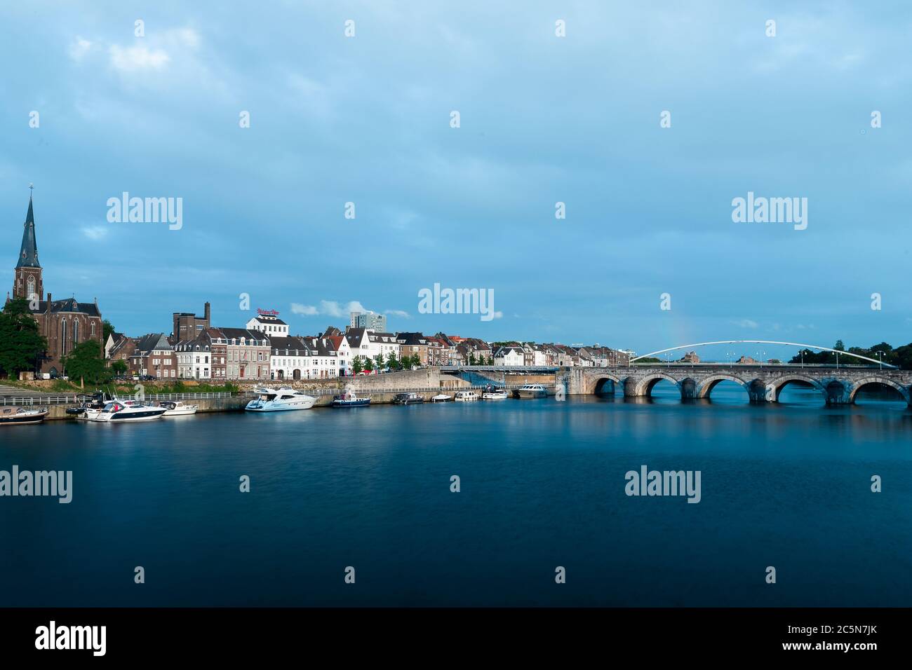 Skyline von Maastricht mit dem kommenden Gebiet Wyck und der Sint Servaas Brücke nach einem Sommerabend Sturm in der goldenen Stunde mit einem Regenbogen zeigen Stockfoto