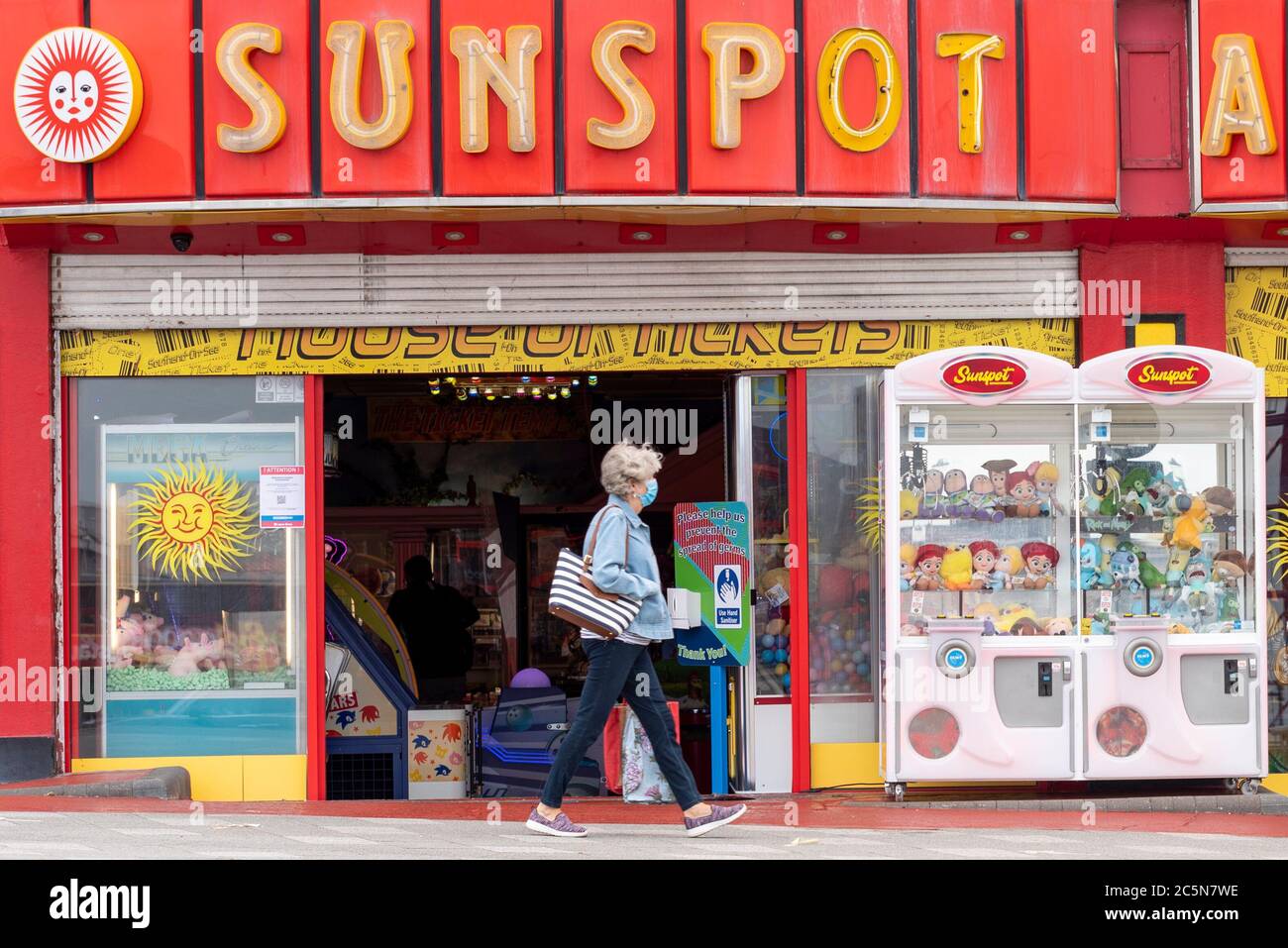 Southend on Sea, Essex, Großbritannien. Juli 2020. Pubs, Restaurants und andere Unternehmen in England können ihre Türen zum ersten Mal seit der COVID-19 Coronavirus-Sperre für Kunden öffnen. Die Regierung erlaubt ihnen, ab 6 Uhr morgens zu öffnen, da Lockdown-Maßnahmen erleichtern. In Southend on Sea haben die Strandpromenade und der Freizeitpark Adventure Island eröffnet, obwohl das kalte, windige Wetter viele Menschen fernhält. Frau in Gesichtsmaske zu Fuß vorbei offen Vergnügungen Geschäft. Nicht hinein gehen Stockfoto