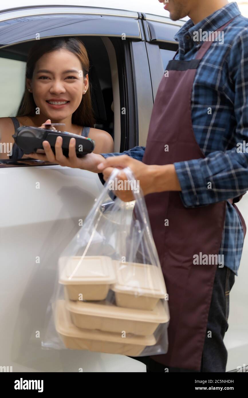 Asiatische Frau Kunden machen mobile Zahlung kontaktlose Technologie auf Drive-Thru-Food-Service-Restaurant während der Abholung. Fahren Sie durch ist neue normale Mo Stockfoto