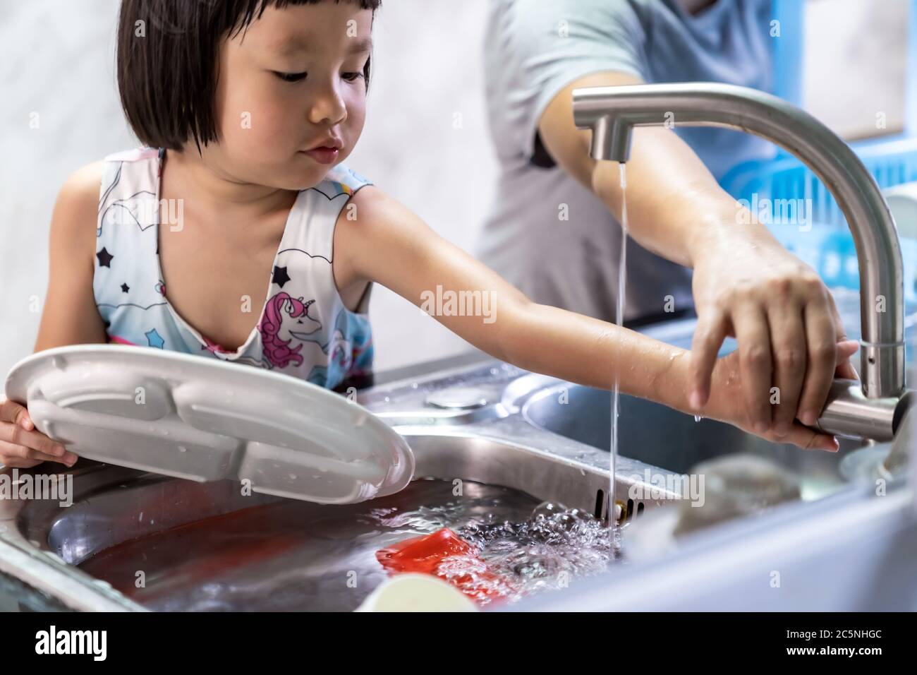 Asiatische Mädchen Waschen Teller und Geschirr mit ihrer Mutter, Hausarbeit für Kind machen Exekutive Funktion für Kind. Houseworking für Kinder lifstyle und Familie konz Stockfoto