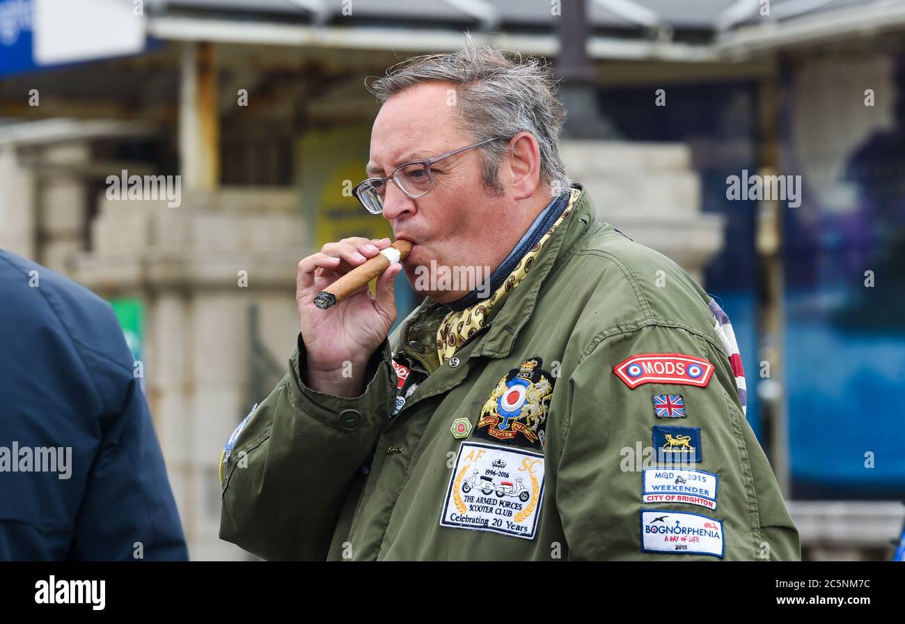 Brighton UK 4. Juli 2020 - Rauchen einer großen kubanischen Zigarre - Mods versammeln sich an der Küste von Brighton, um sich für die Wiedereröffnung des Madeira Drive für den Verkehr zu werben. Die berühmte Straße, wo sie traditionell treffen die meisten Wochenenden wurde durch den stadtrat während der Coronavirus-Krise geschlossen, um soziale Distanzierung zu erleichtern, aber es gibt eine Möglichkeit, es dauerhaft geschlossen . Viele große Veranstaltungen, darunter der London to Brighton Car Run, finden jedes Jahr an der Strandstraße statt : Credit Simon Dack / Alamy Live News Stockfoto