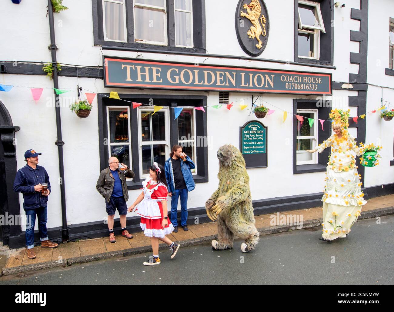 Straßenkünstler treten vor dem Golden Lion Pub in Todmorden, West Yorkshire, für Kunden auf, da es nach der Lockerung der Beschränkungen durch die Coronavirus-Sperre in ganz England wieder eröffnet wird. Stockfoto