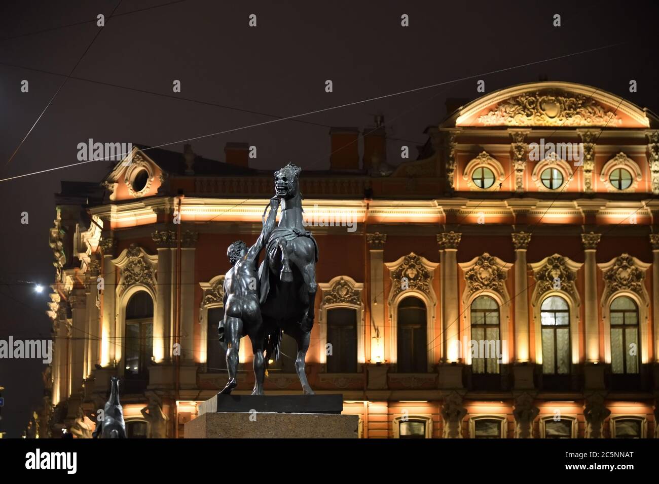 Blick auf die Stadt und Pferdetamper Skulptur des 19. Jahrhunderts von Peter Klodt auf der Anichkov-Brücke in Sankt Petersburg bei Nacht. Russland Stockfoto