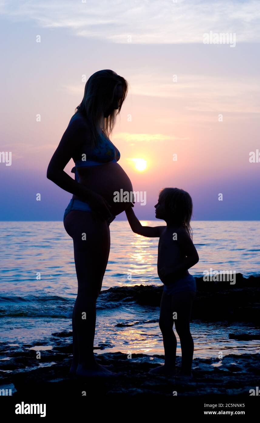 Die schwangere Frau und das kleine Kind (gegen das Meer). Stockfoto