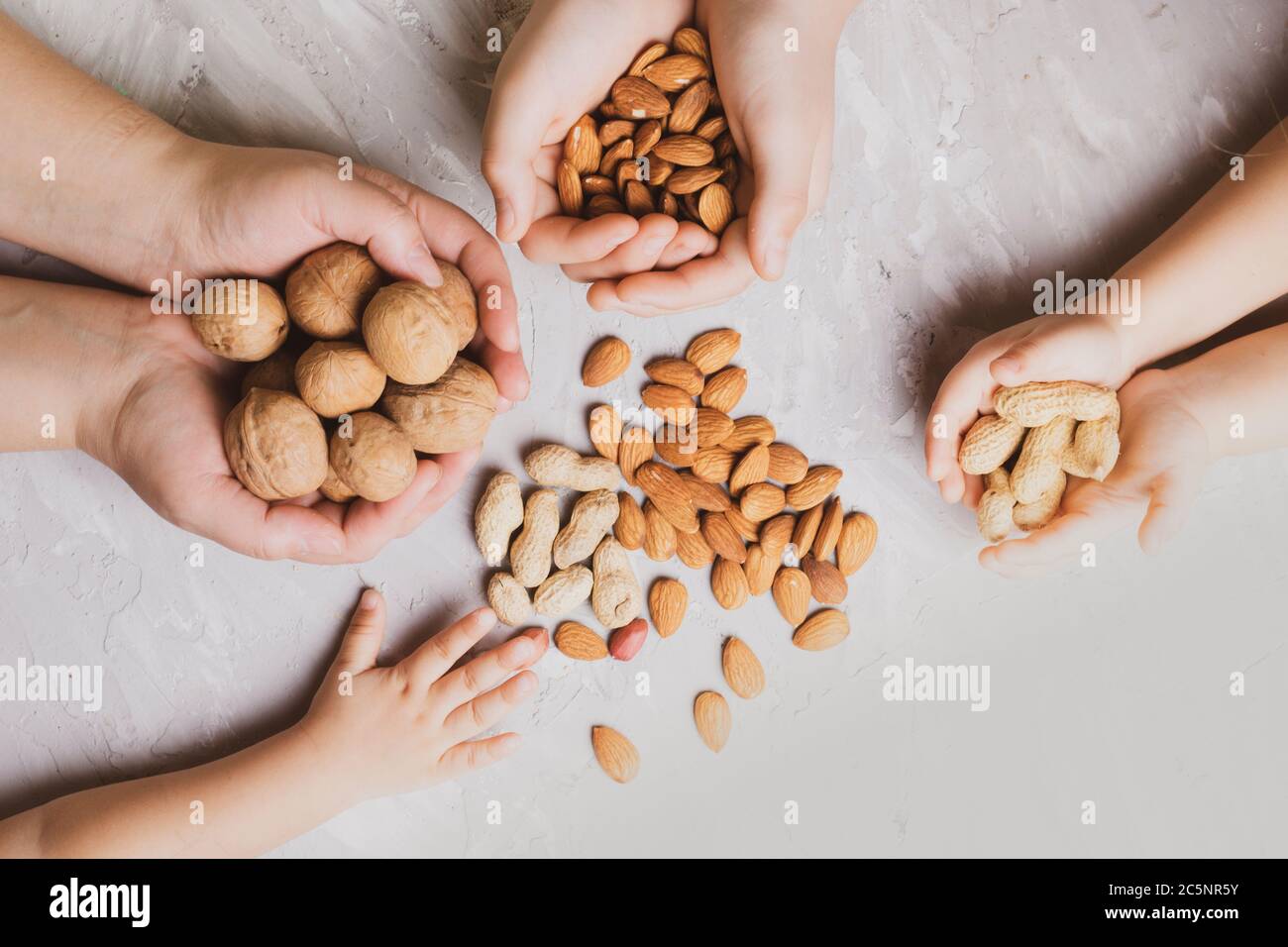 Die Hand der Kinder hält viele Arten von Nüssen, flach legen Stockfoto