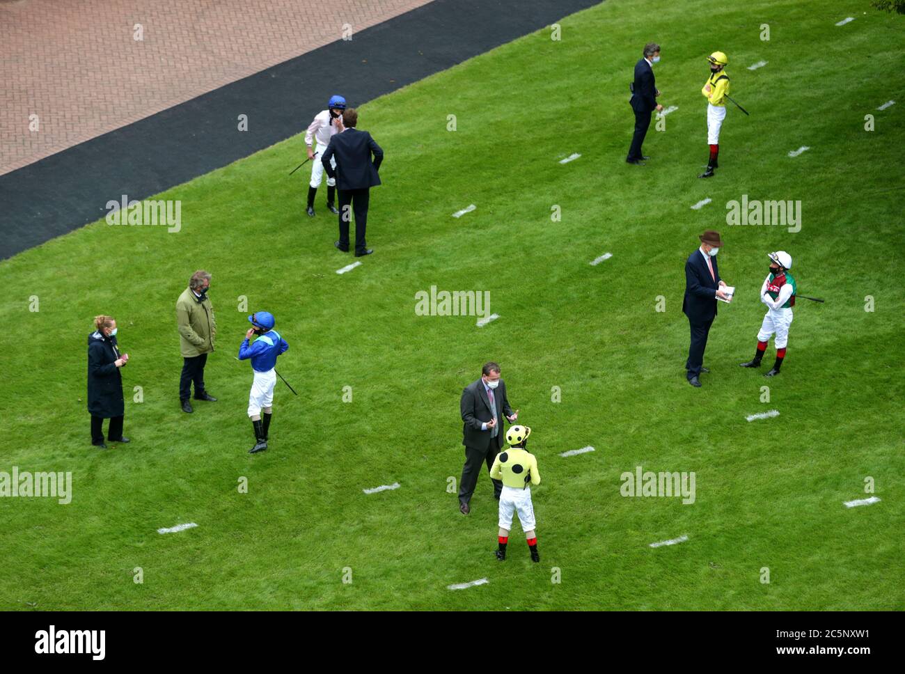 Jockeys und Trainer soziale Distanzierung vor der Prinzessin Elizabeth Stakes auf Epsom Rennbahn. Stockfoto