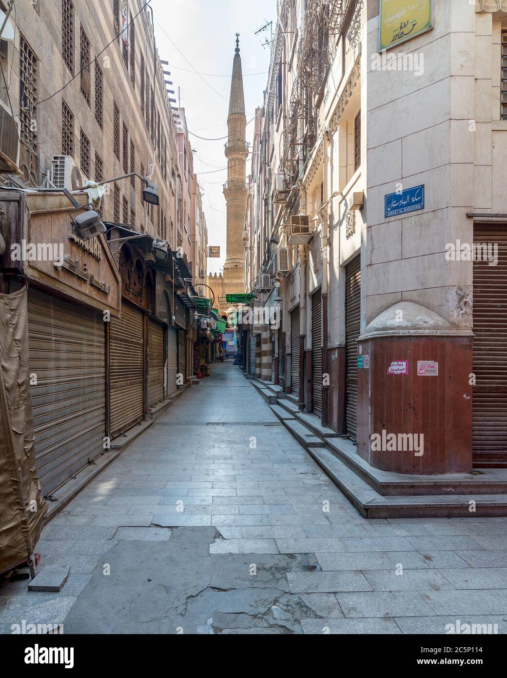 Kairo, Ägypten - Juni 26 2020: Gasse in alten historischen Mamluk Ära Khan al-Khalili berühmten Basar und Souk, mit geschlossenen Geschäften, und Minarett der Al-Hussein Moschee am anderen Ende, während Covid-19 Lockdown Stockfoto