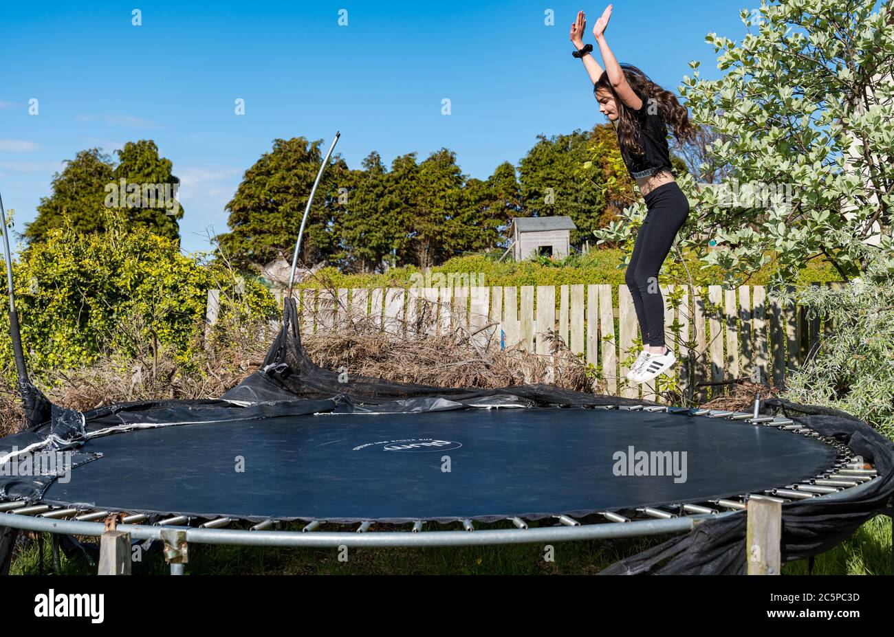 11-jähriges Mädchen, das im sonnigen Garten auf Trampolin springt, East Lothian, Schottland, Großbritannien Stockfoto