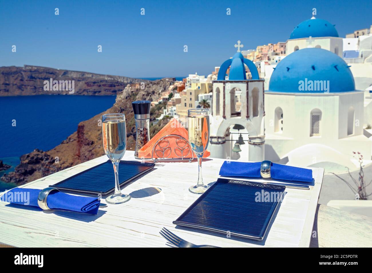 Zwei Gläser Wein auf einem Holztisch vor der Kulisse der Insel Santorini Stockfoto