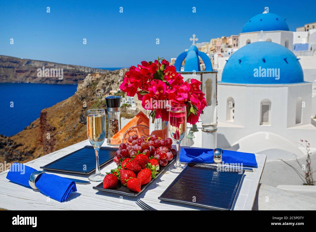 Wein und Obst auf dem Tisch für zwei vor der Kulisse der Insel Santorini Stockfoto