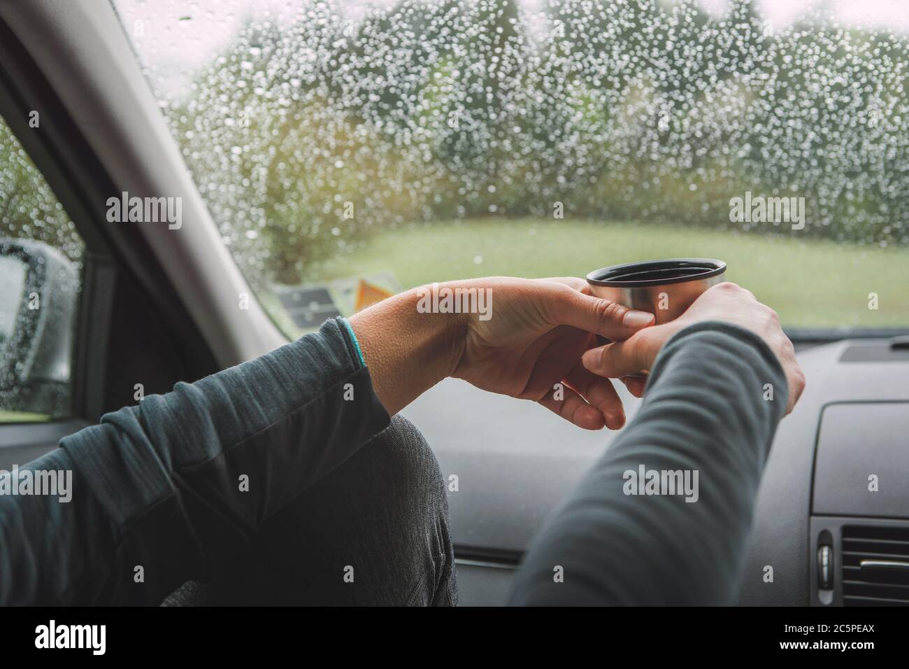 Nahaufnahme von anmutigen weiblichen Palmen halten die heißen Tee Touristen Thermoskanne. Sie sitzt auf Beifahrersitz im modernen Auto, genießen die launische ra Stockfoto