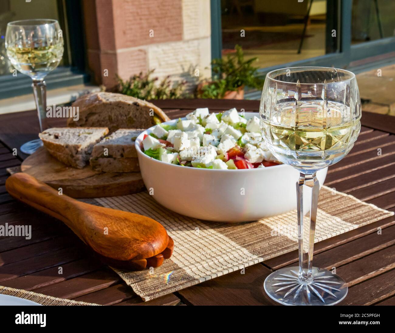 Sommeressen im Freien mit Feta-Salatschüssel, Servierlöffel und frischem Brot und Weißwein in Kristallgläsern, Schottland, Großbritannien Stockfoto