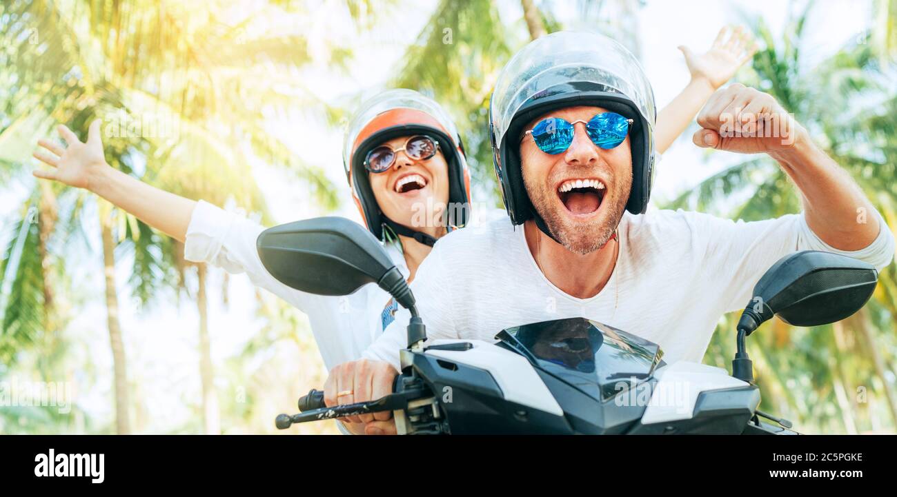 Glücklich lächelndes Paar Reisende Reiten Motorrad Roller in Sicherheitshelmen während tropischen Urlaub unter Palmen auf Ko Samui Insel, Thailand Stockfoto