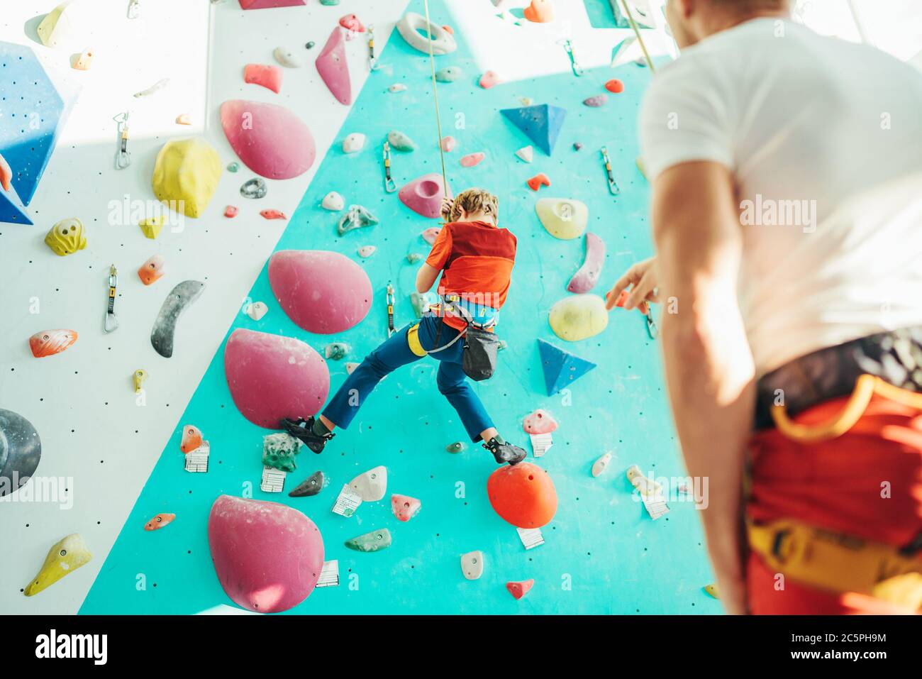 Vater und Teenager Sohn in der Indoor Kletterwand Halle. Boy hängt am Seil  mit einem Klettergurt und Papa ihn auf dem Boden mit einem zu befestigen  Stockfotografie - Alamy