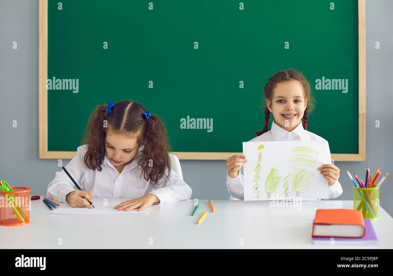 Kleine Mädchen zeichnen während der Kunstklasse in der Schule, kopieren Raum Text. Entzückende Kinder im Unterricht im Klassenzimmer Stockfoto