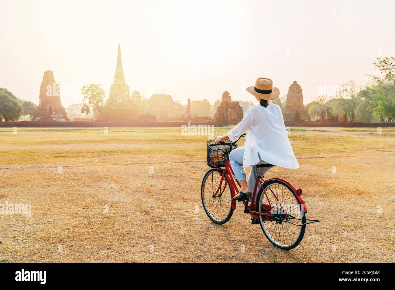 Frau, die ein Fahrrad mit Vorderkorb in der Nähe Ayutthaya historischen Park in Thailand, eine schöne frühe Morgenzeit mit hellem Sonnenaufgangslicht. Carele Stockfoto