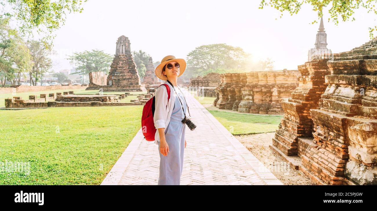 Junge Backpacker Touristische Frau mit einer modernen spiegellosen Kamera, die während ihres Asienurlaubs in Ayutthaya, Thailand, an alten Ruinen spazierengeht. Stockfoto