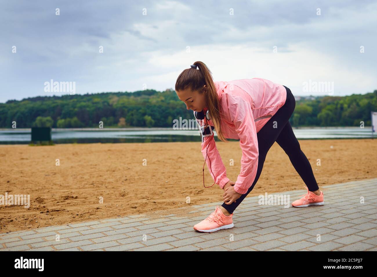 Junge Joggerin, die ihre Beine nach dem Training im Freien streckt. Weibliche Sportlerin macht Übungen nach dem Laufen im Freien Stockfoto