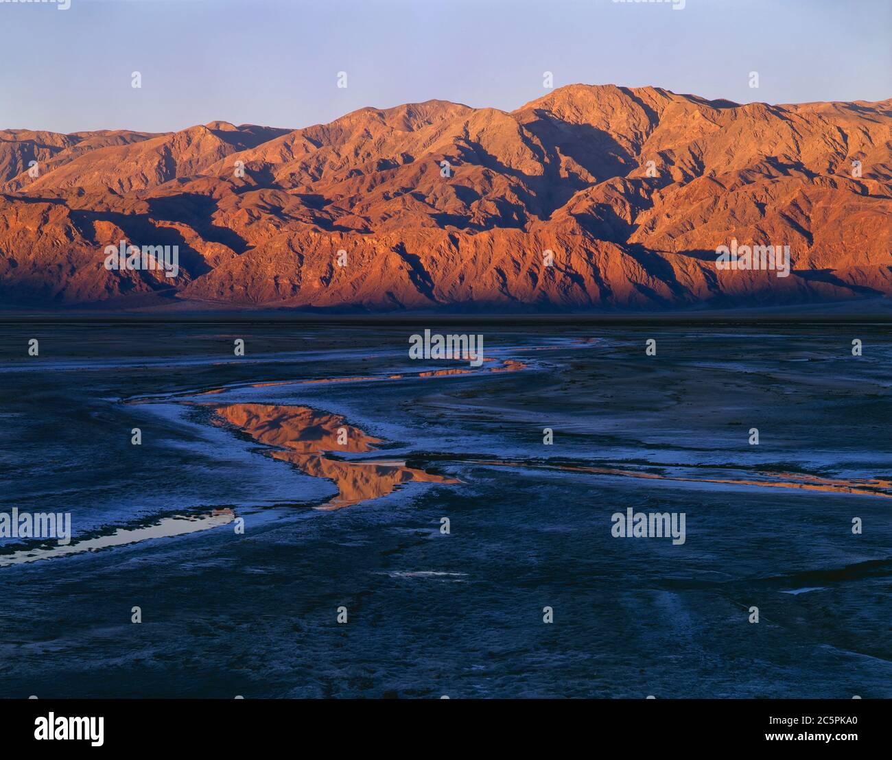 Death Valley National Monument, CA / OCT das erste Licht auf den Panamint Mountains spiegelt sich in den salzverkrusteten Pools auf dem Seenbett bei Badwater. Stockfoto