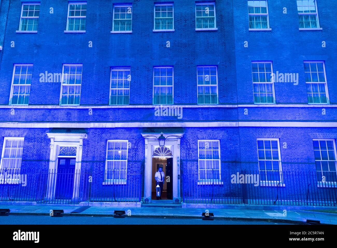 04. Juli 2020. London, Großbritannien. Ein Mitarbeiter stellt eine Kerze an der Vorderseite der Downing Street auf, da das Gebäude mit blauer Beleuchtung beleuchtet wird, um den 72. Geburtstag des National Health Service zu feiern. Foto von Ray Tang/Ray Tang Media Stockfoto