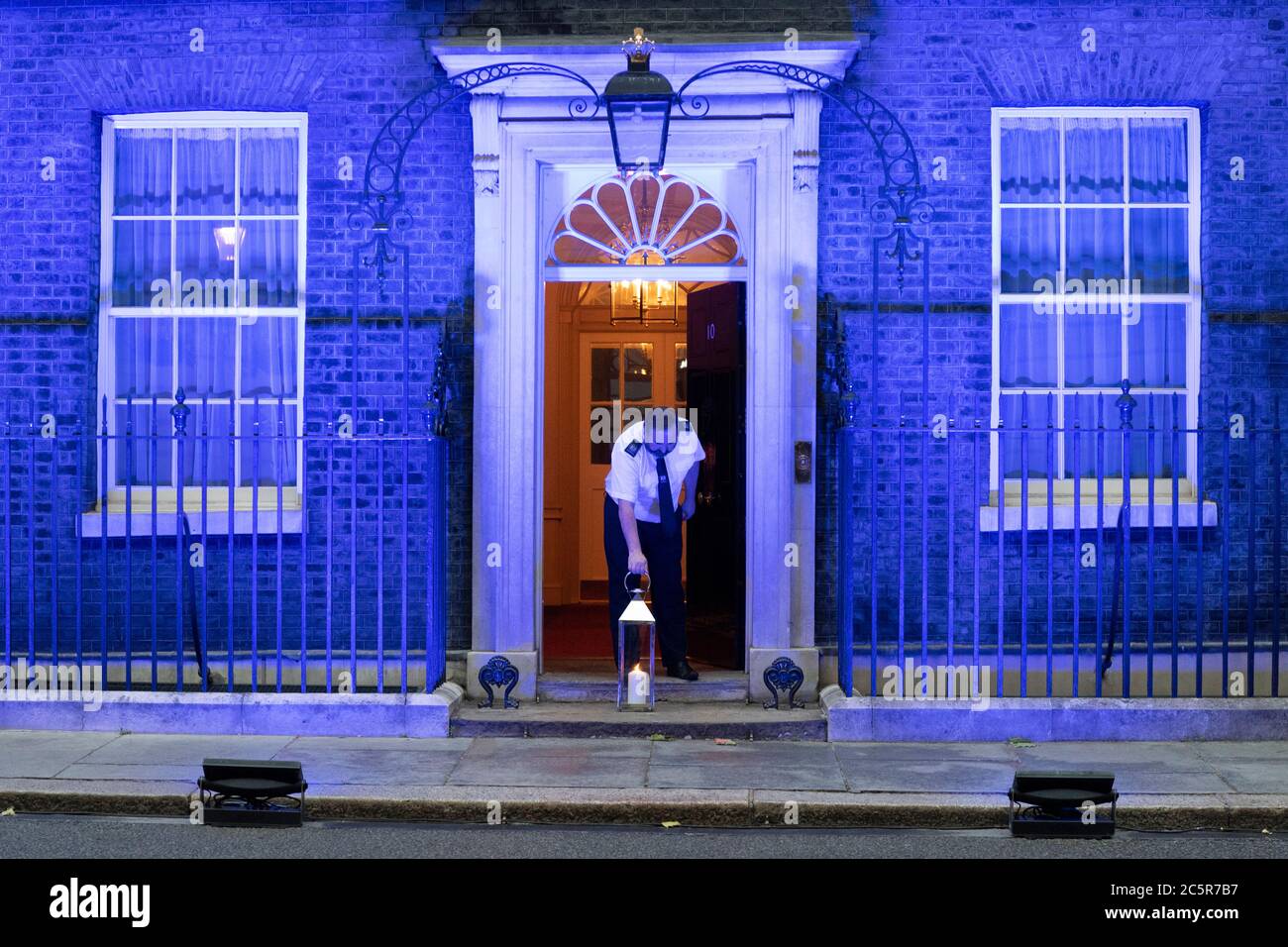 04. Juli 2020. London, Großbritannien. Ein Mitarbeiter stellt eine Kerze an der Vorderseite der Downing Street auf, da das Gebäude mit blauer Beleuchtung beleuchtet wird, um den 72. Geburtstag des National Health Service zu feiern. Foto von Ray Tang/Ray Tang Media Stockfoto