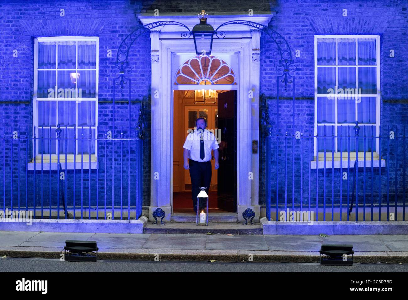 04. Juli 2020. London, Großbritannien. Ein Mitarbeiter stellt eine Kerze an der Vorderseite der Downing Street auf, da das Gebäude mit blauer Beleuchtung beleuchtet wird, um den 72. Geburtstag des National Health Service zu feiern. Foto von Ray Tang/Ray Tang Media Stockfoto