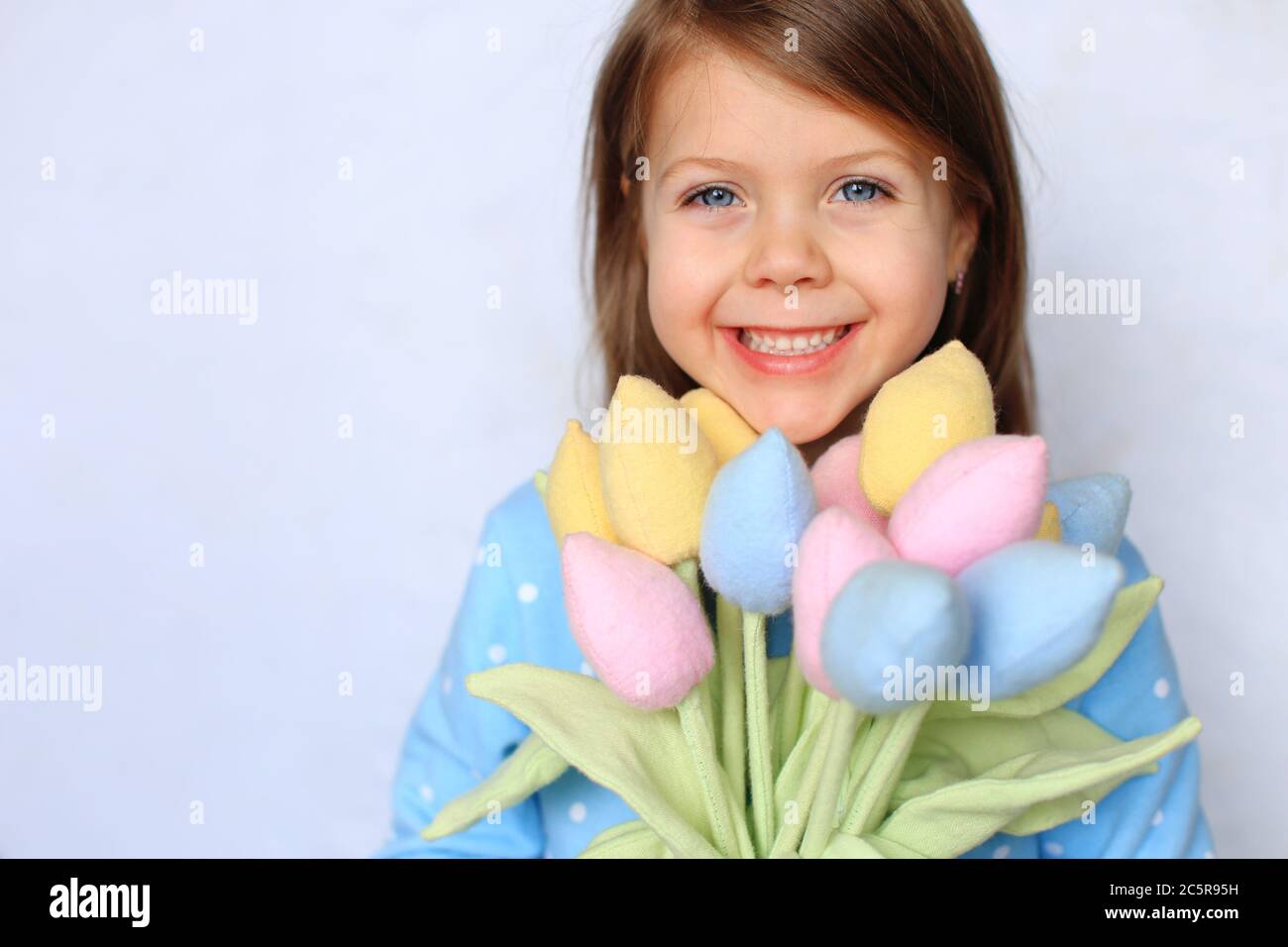 Schöne blauäugige Mädchen steht mit Blumen in den Händen Stockfoto