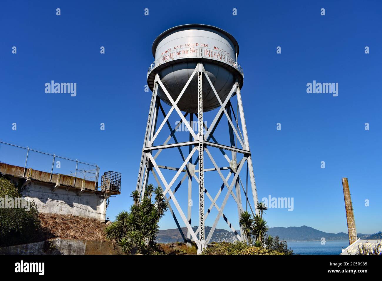 Der graue Wasserturm auf Alcatraz Island, mit roten Graffiti bedeckt. Frieden und Freiheit, Heimat der Freien, Willkommen Indianer. San Francisco, Kalifornien Stockfoto