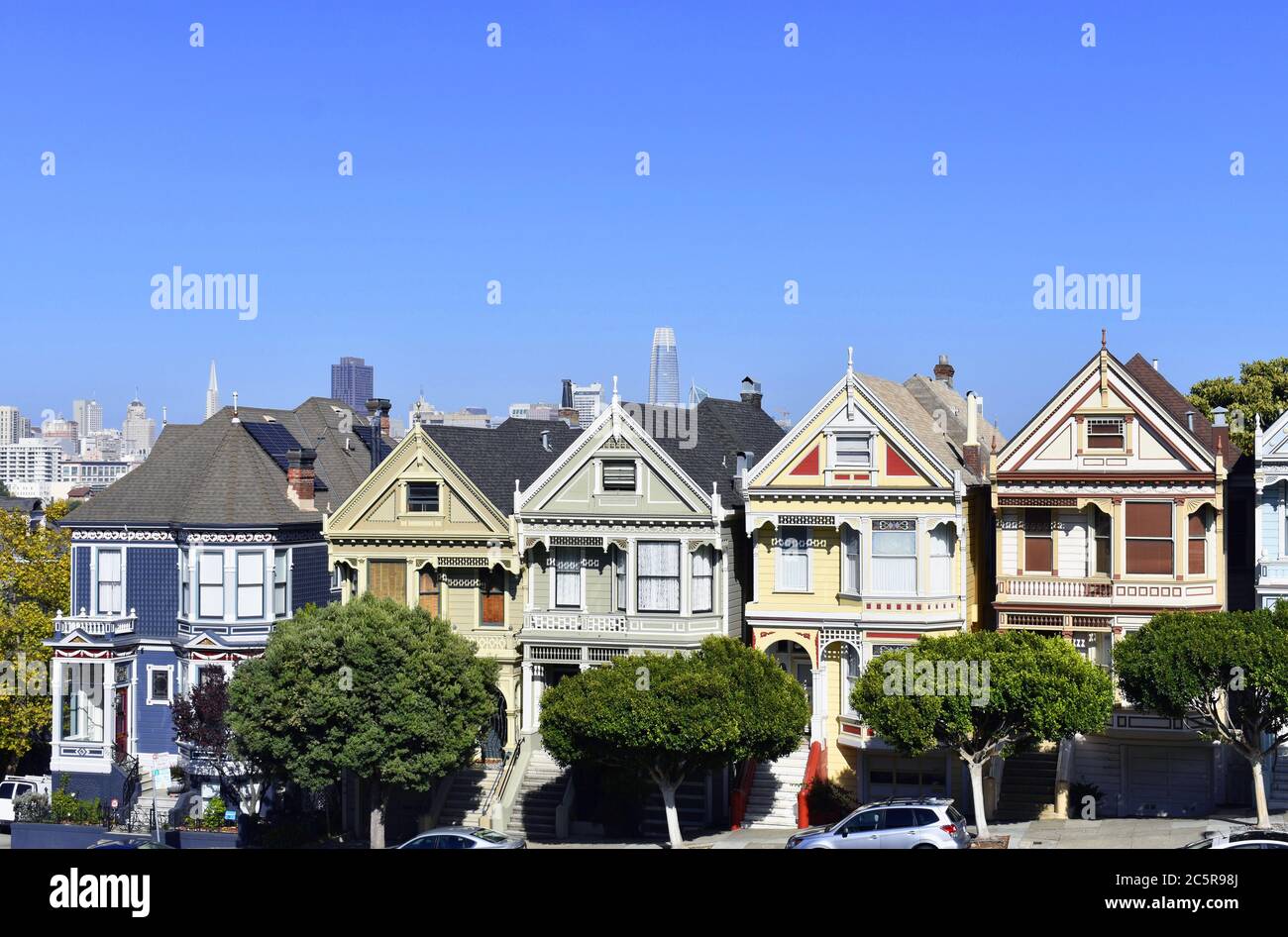 Die Painted Ladies aus dem Alamo Square Park. Die Skyline von San Francisco und die Transamerica Pyramide sind hinter den viktorianischen Häusern zu sehen. Stockfoto