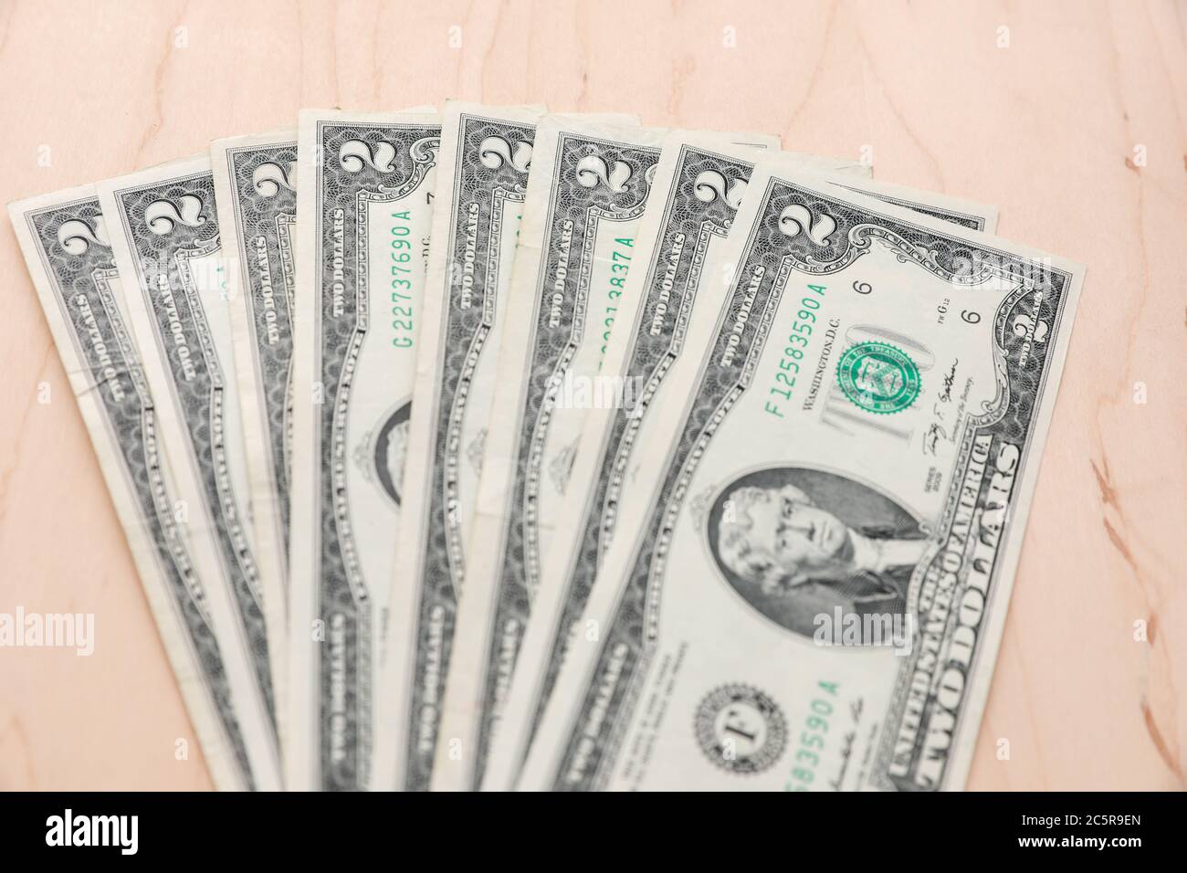 Fan von mehreren zwei Dollar Scheine auf einem hellen Holz strukturierten Hintergrund. Stockfoto