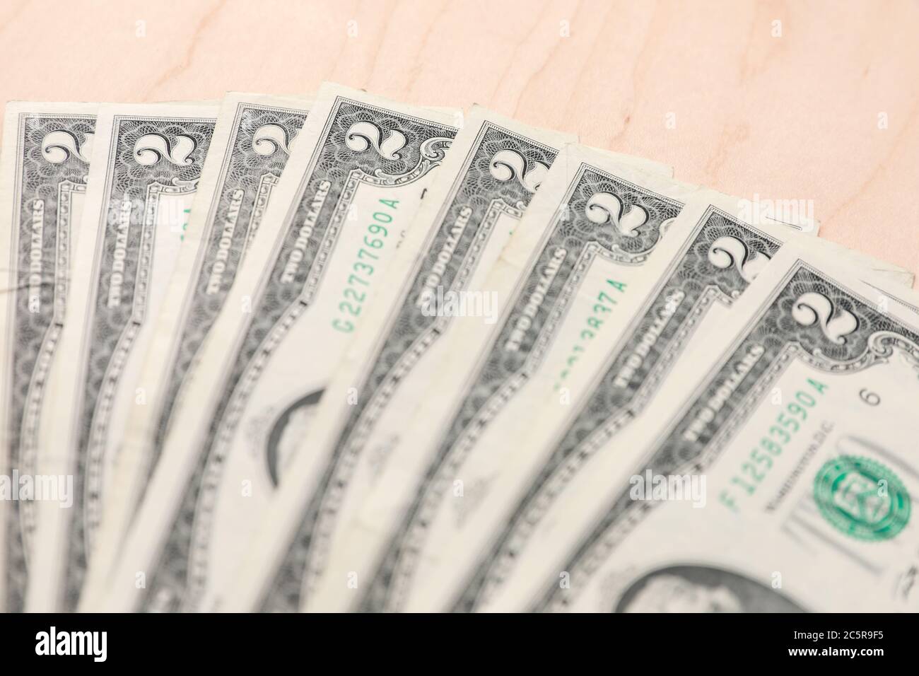 Fan von mehreren zwei Dollar Scheine auf einem hellen Holz strukturierten Hintergrund. Stockfoto