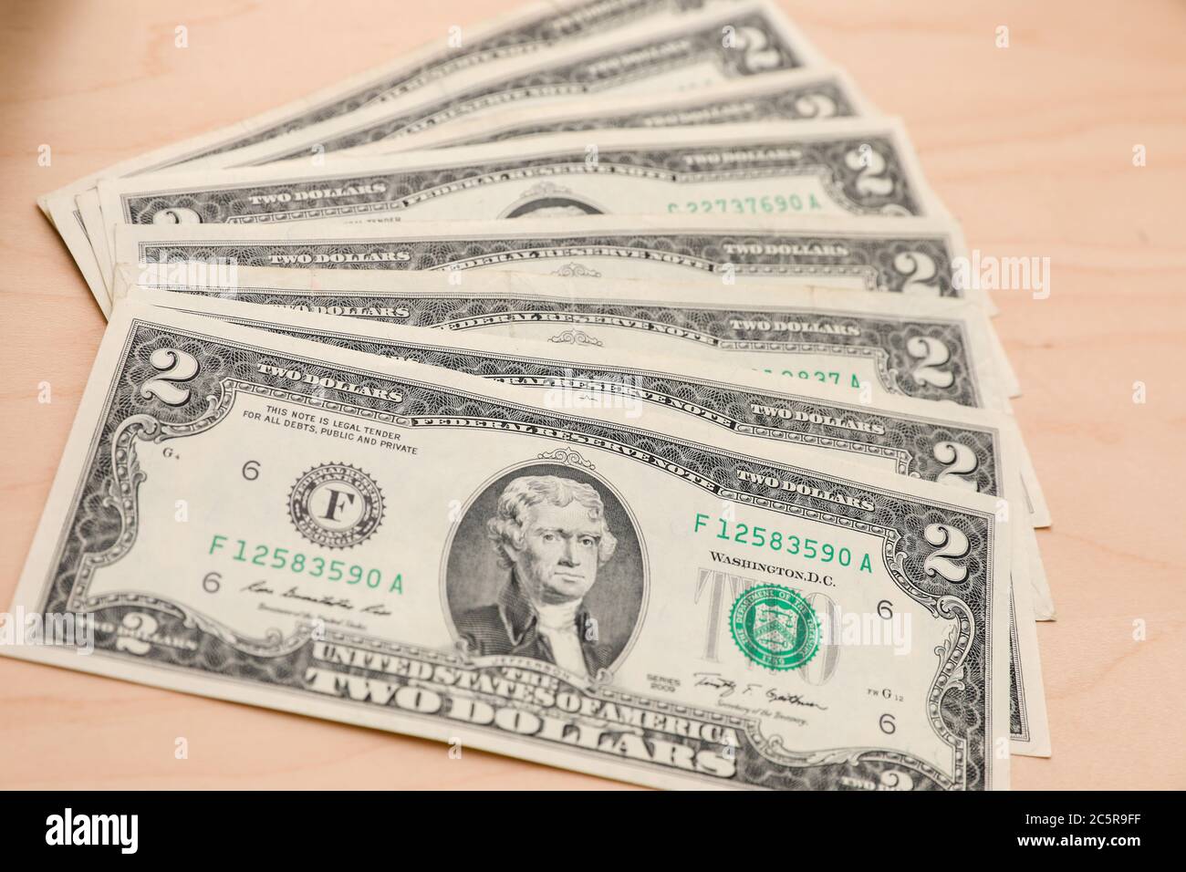 Fan von mehreren zwei Dollar Scheine auf einem hellen Holz strukturierten Hintergrund. Stockfoto