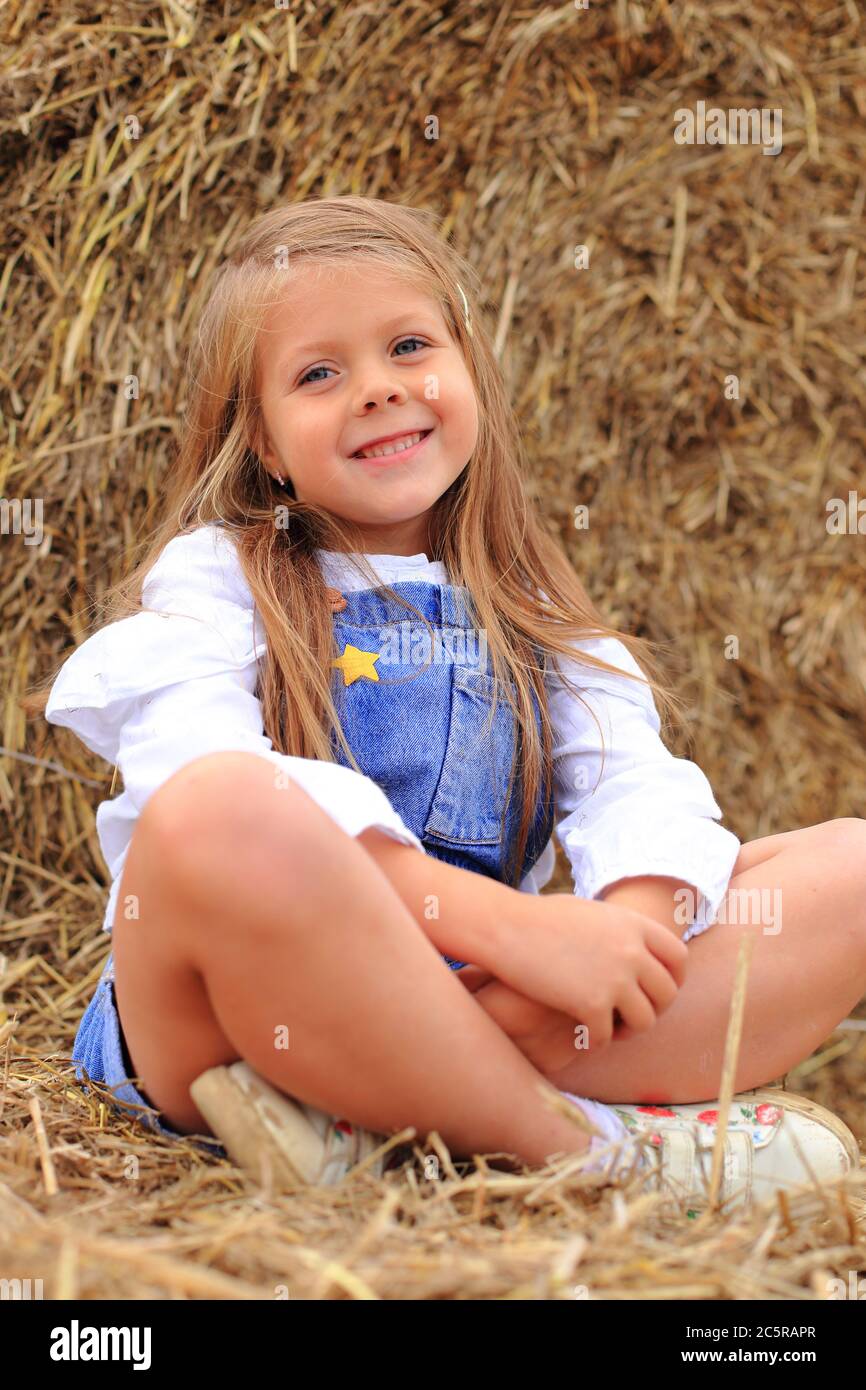 Porträt eines kleinen Mädchens auf einem Heuhaufen im Sommer. Stockfoto