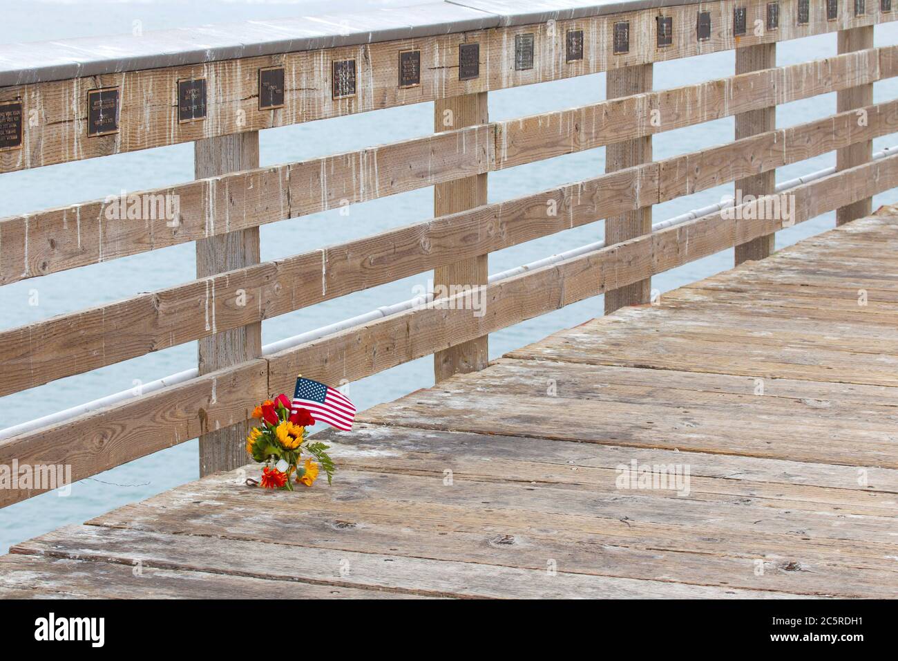 Kleines Blumendenkmal und amerikanische Flagge auf Cayucos Pier Stockfoto