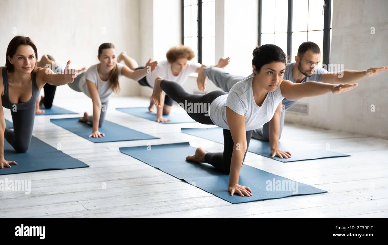 Aktive multirassische Menschen tun parsva balasana drinnen. Stockfoto