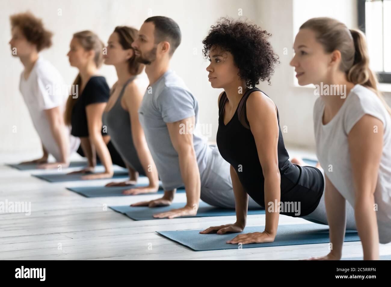 Junge gesunde gemischte Rennen sportliche Menschen üben Cobra Pose. Stockfoto