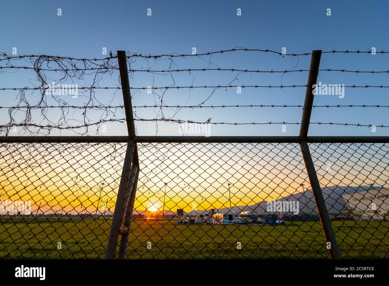 Sicherheitszaun am Flughafen bei Sonnenuntergang. Stockfoto