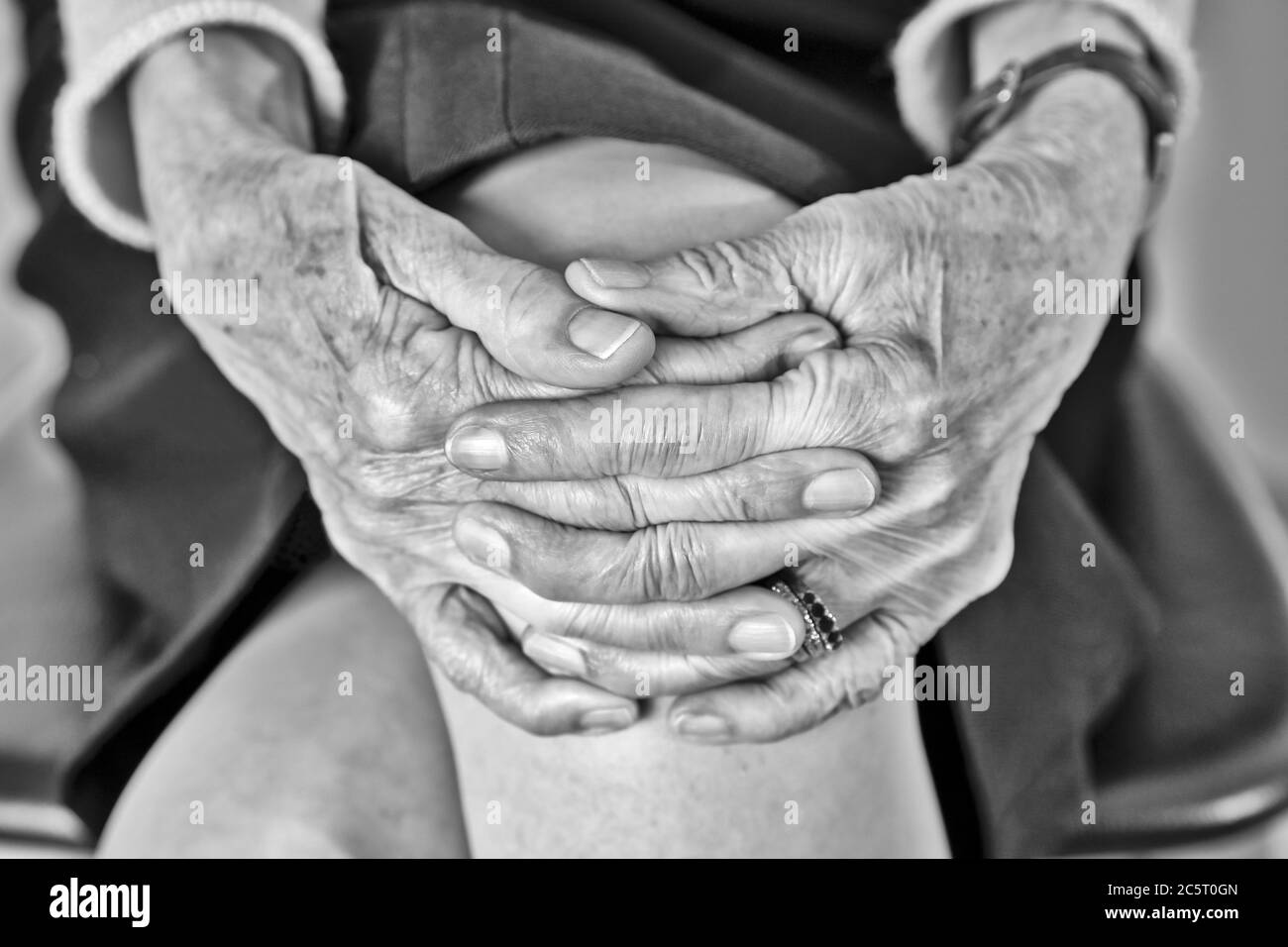 Ältere Frau mit verbundenen Händen sitzend Stockfoto