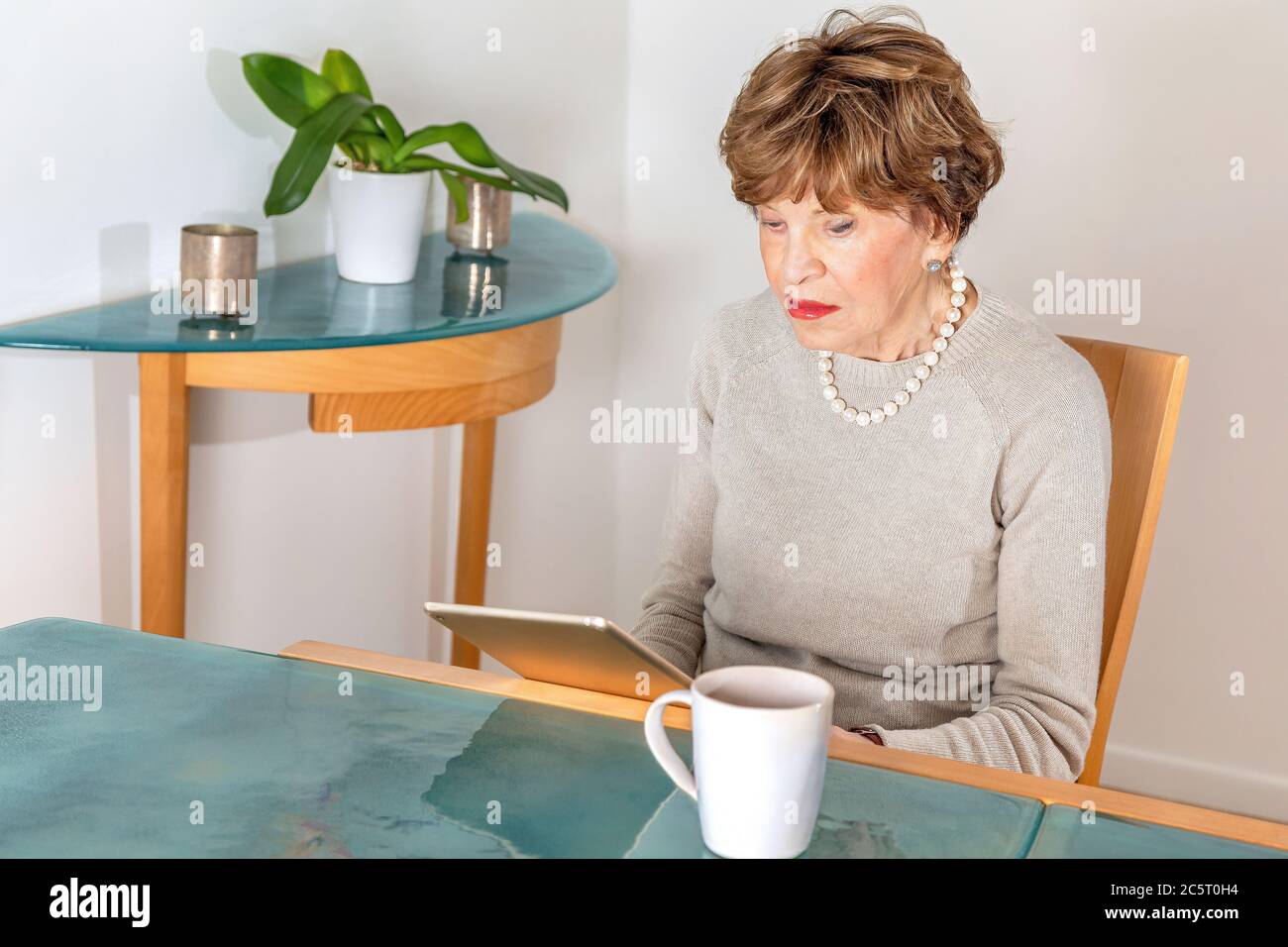 Achtzig Jahre alte elegante Frau liest ihr ipad Stockfoto