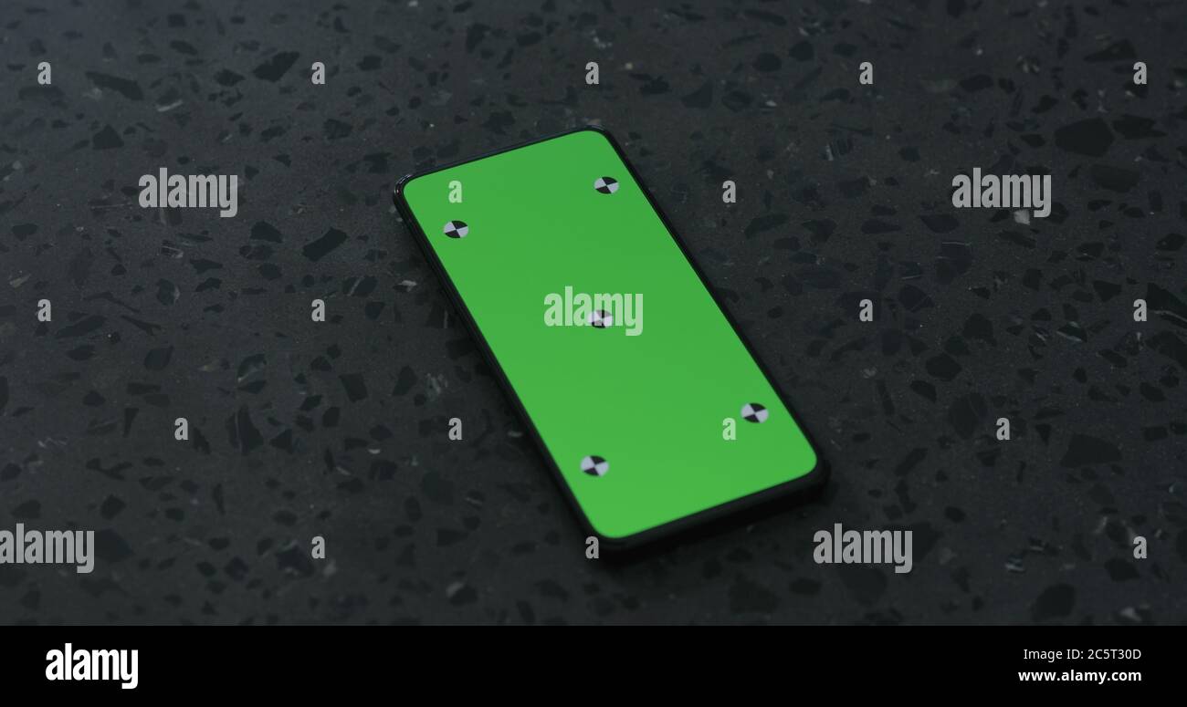 Smartphone mit grünem Bildschirm auf Terrazzo-Oberfläche Stockfoto