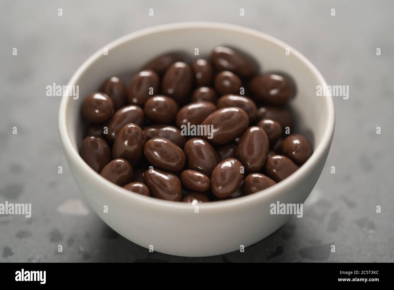 Milchschokolade-Dragee in weißer Schale auf Beton-Hintergrund Stockfoto