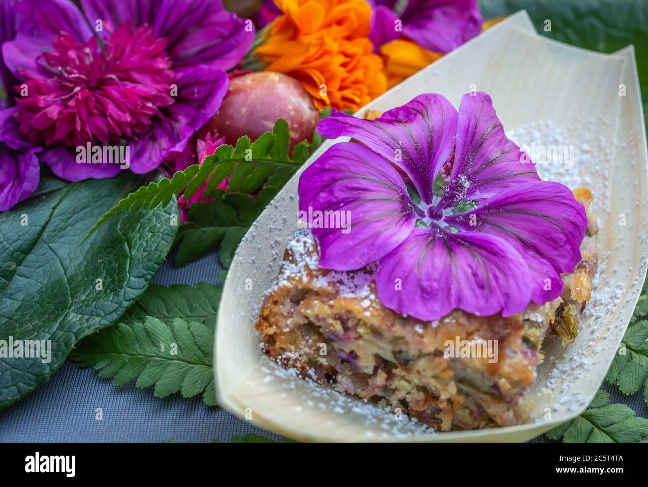 Süß mit Malbe und Mandeln.Teller mit Malwee Blumen verziert. Blumenfutter Konzept. Essbare Sommerblumen Stockfoto