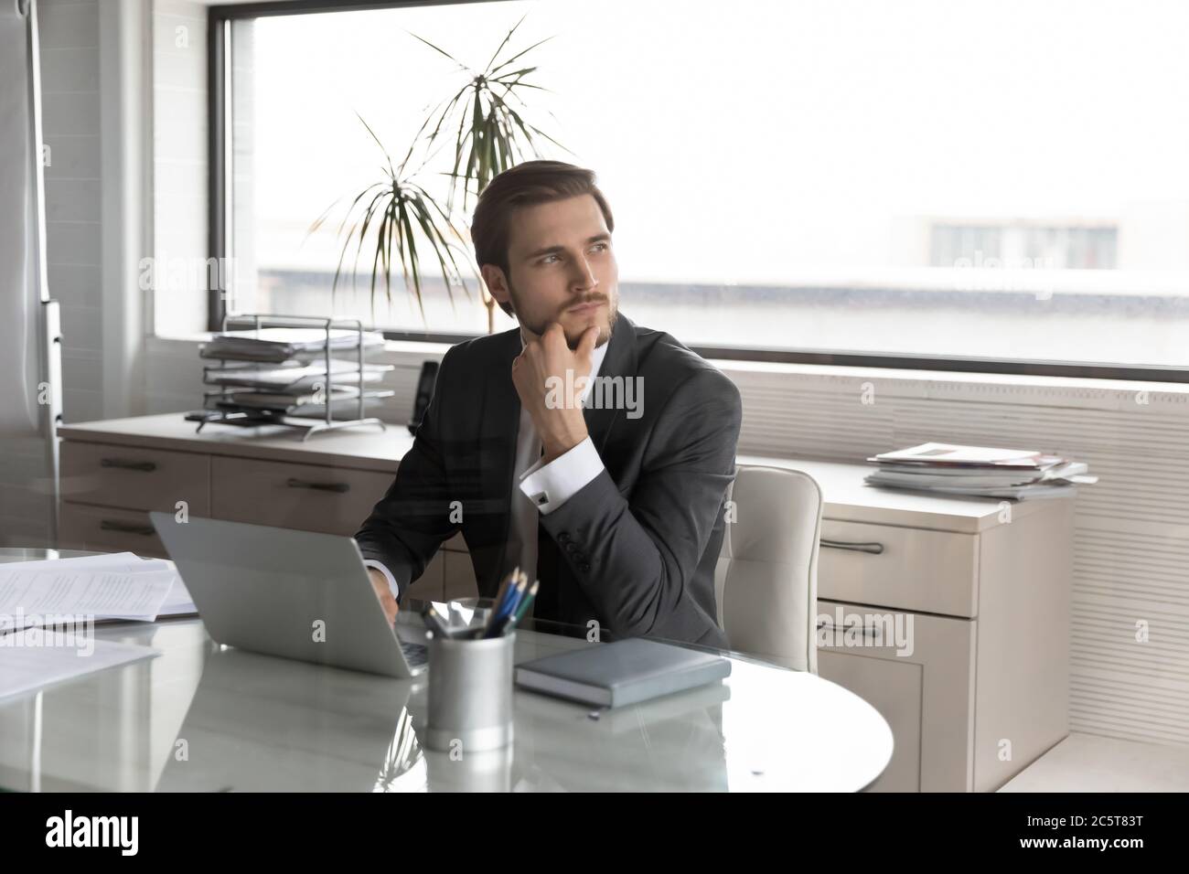 Durchdachte männliche CEO arbeiten an Laptop-Entscheidungen Stockfoto