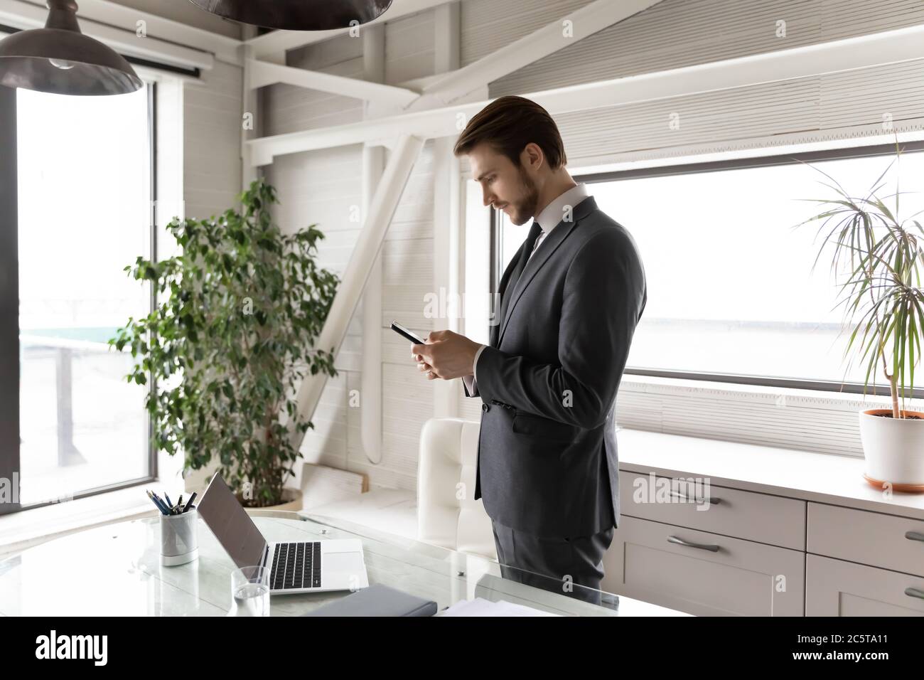 Junge kaukasische CEO mit Gadgets in eigenen Büro Stockfoto
