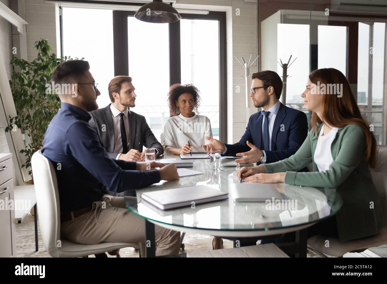 Mitarbeiter aus verschiedenen Rassen treffen sich in der Vorstandsetage, die an Teamdiskussionen beteiligt ist Stockfoto