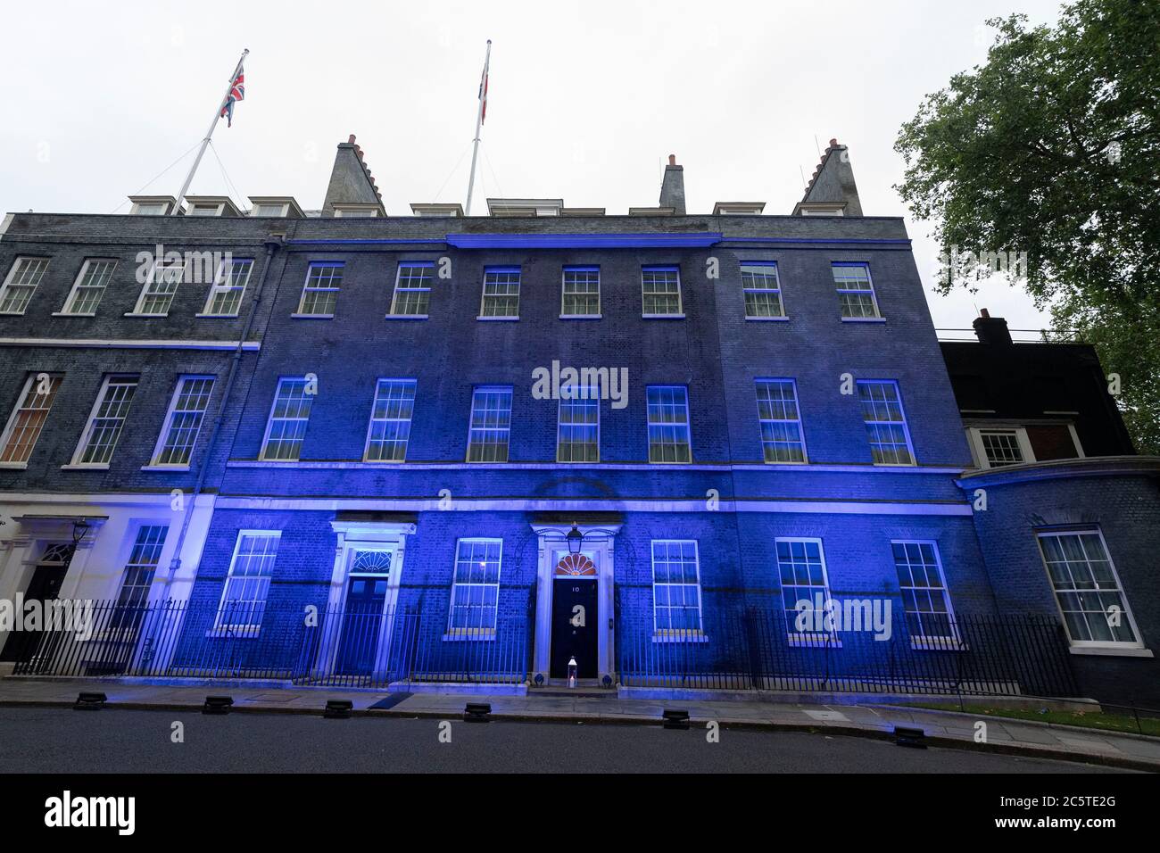 London, Großbritannien. Juli 2020. Eine Kerze wird vor der Downing Street aufgestellt, während das Gebäude blau angezündet wird, um den 72. Jahrestag des National Health Service (NHS) in London, Großbritannien am 4. Juli 2020 zu begehen. Laut lokalen Medien wurden Dutzende von Wahrzeichen im ganzen Land blau beleuchtet, um 72 Jahre seit der Gründung des NHS zu markieren. Quelle: Ray Tang/Xinhua/Alamy Live News Stockfoto