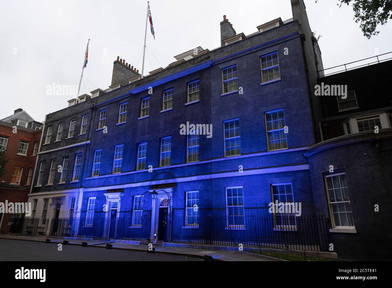 London, Großbritannien. Juli 2020. Eine Kerze wird vor der Downing Street aufgestellt, während das Gebäude blau angezündet wird, um den 72. Jahrestag des National Health Service (NHS) in London, Großbritannien am 4. Juli 2020 zu begehen. Laut lokalen Medien wurden Dutzende von Wahrzeichen im ganzen Land blau beleuchtet, um 72 Jahre seit der Gründung des NHS zu markieren. Quelle: Ray Tang/Xinhua/Alamy Live News Stockfoto