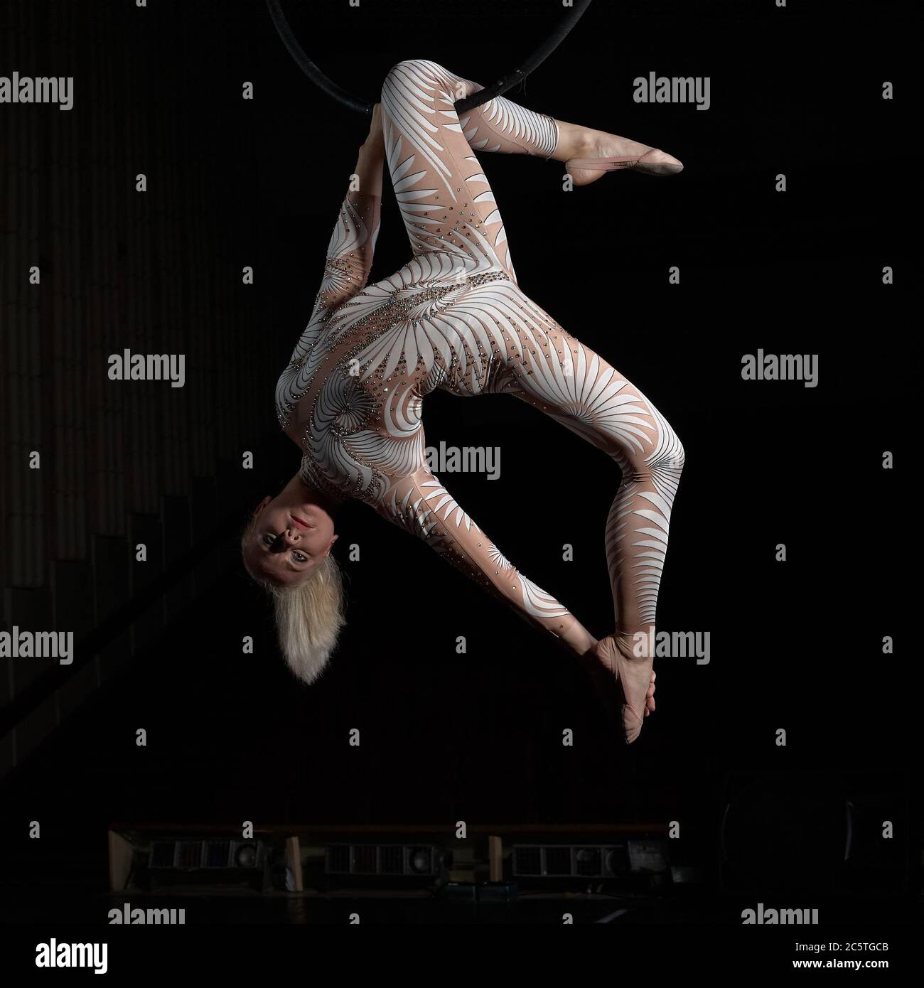 Der akrobat führt einen Stunt am Luftring durch. Mädchen in einem Anzug für Aufführungen. Stockfoto